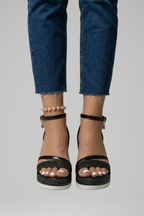 Black cushioned orthopedic sandals worn with jeans, front view