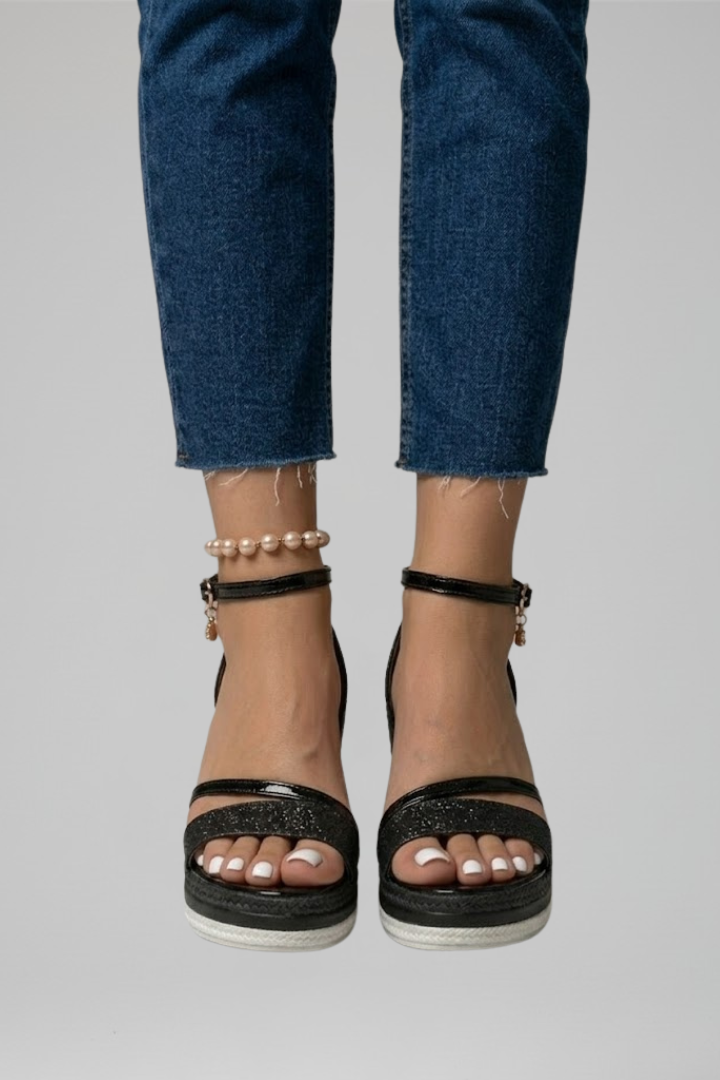 Black cushioned orthopedic sandals worn with jeans, front view