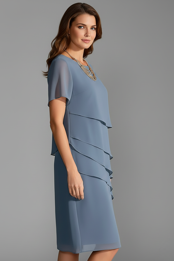 Woman wearing a blue layered short sleeve dress, side angle
