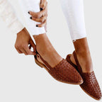 Women's woven slingback flats in brown, being fastened on the foot