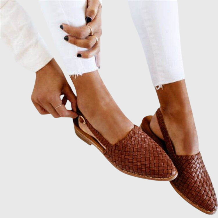 Women's woven slingback flats in brown, being fastened on the foot