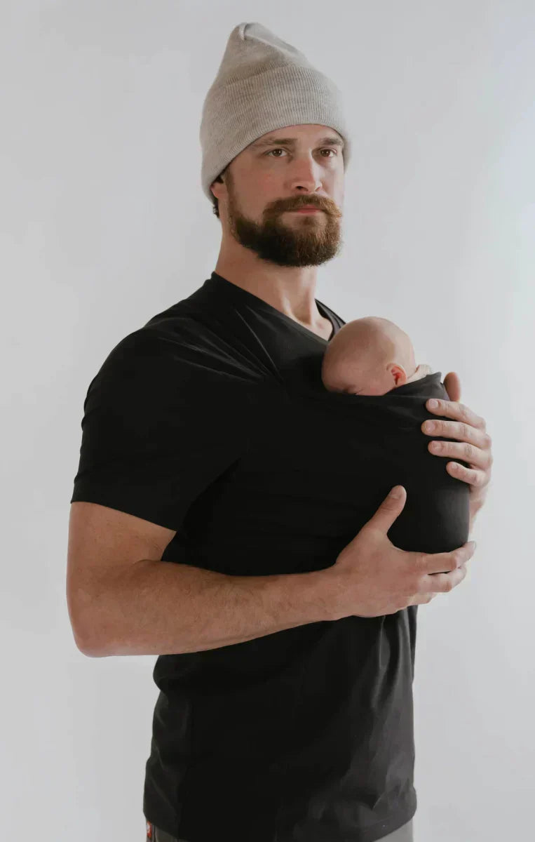 Man wearing the Black CuddleNest kangaroo shirt with baby supported