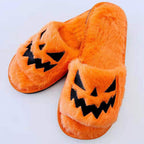 Orange plush Halloween slippers with black jack-o'-lantern face
