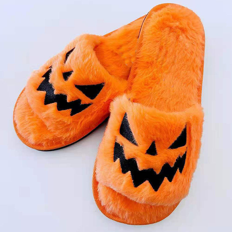 Orange plush Halloween slippers with black jack-o'-lantern face