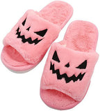 Pair of pink plush Halloween slippers with black jack-o'-lantern face
