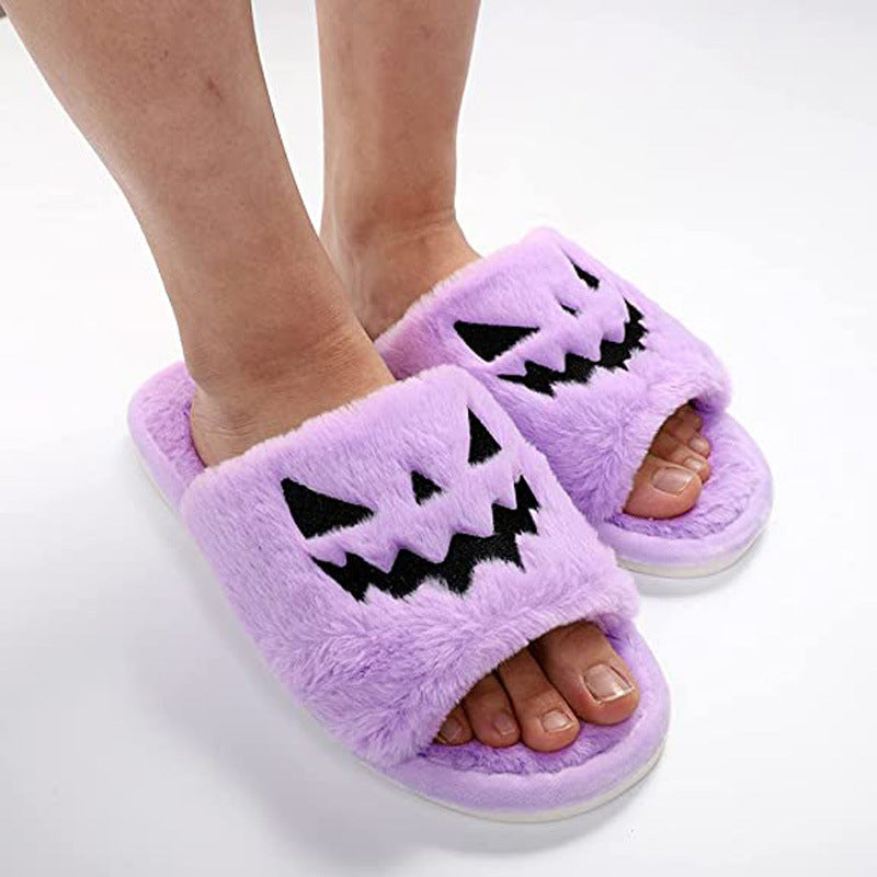 Purple plush Halloween slippers worn on feet with black jack-o'-lantern face