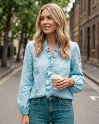Woman wearing frilly ruffle top in blue on a city street